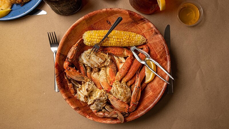 Overhead shot of bowl of crabs pieces and a side of corn on the cob